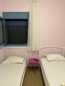 two beds in a room with a window and a table at Theros house in Kythira