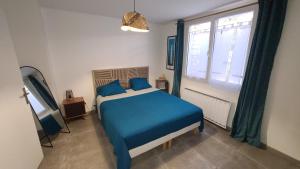 a bedroom with a blue bed and a window at Les Geais Bleus in Royan