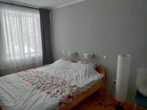 a bed with a white blanket with flowers on it at Located in Ances pagasts Apartments in Ance