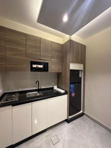 a kitchen with white cabinets and a black refrigerator at Chic Apartments For Rent ave2-4 in Amman