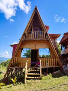 a woman sitting on the porch of a thatched house at Casa Alpina - Barlovento Ecolodge Tarapoto - Familiar in Tarapoto
