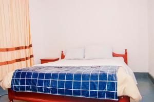 une chambre avec un lit avec une couverture bleue et blanche dans l'établissement Eco Cottage BnB, à Ruhengeri