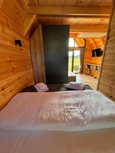 a large bed in a room with wooden walls at Eternum Glamping in Žabljak