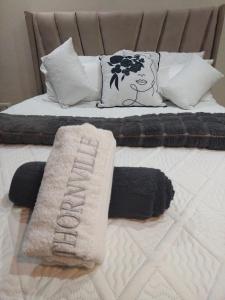 Cama con almohadas blancas y negras y manta en Thornville Guest house Platinum, en Pietermaritzburg