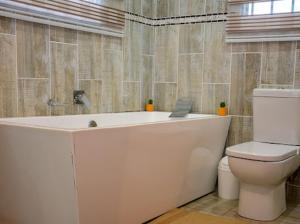 Un baño con bañera blanca y un inodoro. en Thornville Guest house Platinum, en Pietermaritzburg