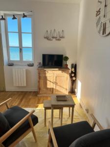 Una sala de estar con una mesa y un televisor. en Belle vue sur la mer, en Veules-les-Roses