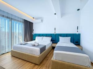 two beds in a room with blue walls and windows at Zace Studios in Ksamil