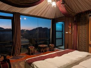 a bedroom with a bed and a large window at Wadi Rum Majestic Camp in Wadi Rum