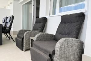 Zwei Korbstühle stehen neben einem Fenster in der Unterkunft Gran Canet Vlado in Canet d'en Berenguer