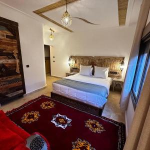 a bedroom with a large bed and a red rug at Dar Rihana Dadès in Aït Idaïr