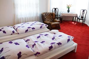 a bedroom with two beds and a chair and a table at Pension De Lux Königsbrunn in Königsbrunn