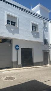 a white building with a garage and two windows at Casa MAC in Chiclana de la Frontera