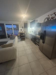 a kitchen with a refrigerator and a couch in a room at Appartement bella vista marseillan in Marseillan