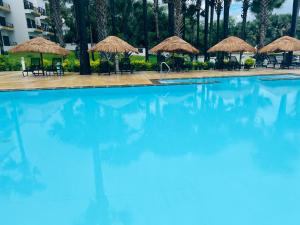 a swimming pool with chairs and umbrellas at Relax Oceanfront Suites in Sere Kunda