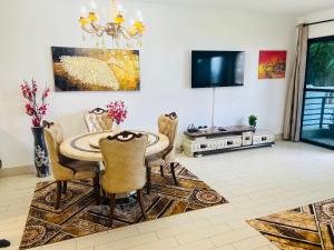 a dining room with a table and chairs and a tv at Relax Oceanfront Suites in Sere Kunda