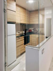 een keuken met houten kasten en een witte koelkast bij Apartamento Viktory New York in Valladolid +4 foto's