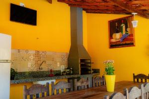 a kitchen with yellow walls and a table with chairs at Pousada Brilho do Sol in Serra Negra