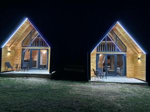 a wooden house with two windows and chairs at night at Eternum Glamping in Žabljak