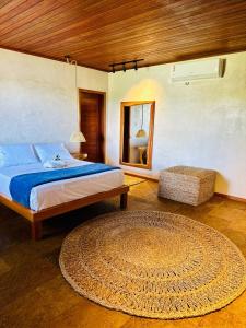 a bedroom with a bed and a rug and a mirror at Casa Taquirí in Santo Amaro
