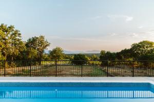a swimming pool with a fence and trees at Olives Garden in Čitluk