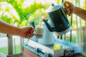 a person is holding a coffee maker with a cup at Pousada Brilho do Sol in Serra Negra