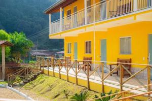 a yellow house with a porch and a balcony at Pousada Brilho do Sol in Serra Negra