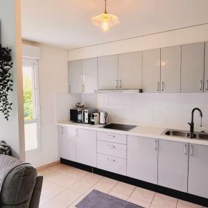 a kitchen with white cabinets and a sink at Appartement Saint-Denis proche Stade de France in Saint-Denis