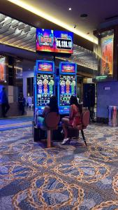 zwei Personen sitzen vor einem Spielautomaten in einem Casino in der Unterkunft Punta cana bavaro hotel beach in Punta Cana