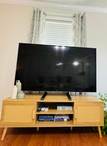 a large flat screen tv on a wooden entertainment center at Countryside Carriage House with Pool in Commerce