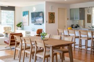 Una cocina y una sala de estar con una mesa y sillas de madera. en Penthouse on the Ritz - Oceanstays, en Yamba