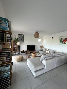 a living room with a white couch and a tv at Villa cosy toute équipée avec piscine in Le Gosier