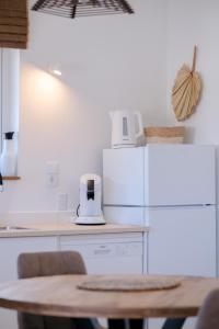 een keuken met een tafel en een witte koelkast bij Tiki Blou - Mini resort centraal gelegen tussen Mambo Beach & Jan Thiel in Willemstad