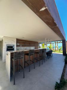 an open kitchen with a bar with stools at Mirante do porto in Porto De Galinhas