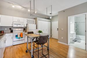 a kitchen with white cabinets and a table with a chair at CozySuites Mill District with pool, gym #11 in Minneapolis +30 photos