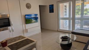 a living room with a glass table and a tv at Apartman Riba in Biograd na Moru