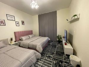 New cairoにあるMivida Coco apartmentのベッド2台とテレビがあるホテルの部屋 +43枚の写真