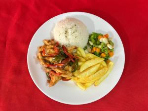 a plate of food with rice and vegetables on a red table at Hotel Espindola in Tulcán
