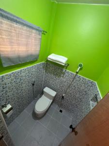 a bathroom with a toilet and a green wall at AGs Place in Tagbilaran City +13 photos