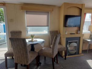 a living room with a table and chairs and a fireplace at Haven Devon Cliffs Caravan in Budleigh Salterton