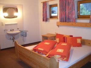 Bett mit orangefarbenen Kissen und Waschbecken im Zimmer in der Unterkunft Apartment Christine Öttl in Pfunds