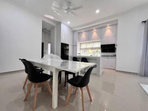 a white kitchen with a table and black chairs at Melur House - Private Pool, Jacuzzi, Bbq, Netflix, PS4 in Malacca