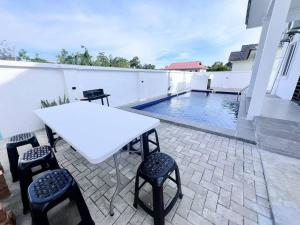a white table and chairs on a patio with a swimming pool at Melur House - Private Pool, Jacuzzi, Bbq, Netflix, PS4 in Malacca