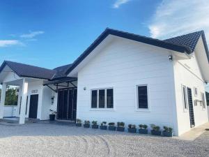 a white house with a black roof at Melur House - Private Pool, Jacuzzi, Bbq, Netflix, PS4 in Malacca