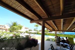 a group of people sitting under a pavilion at a resort at Flat Luxo no Laguna Beach in Porto De Galinhas