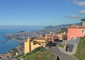 uma cidade numa colina com o oceano ao fundo em Balancal Apartments and Villas Palheiro Village no Funchal