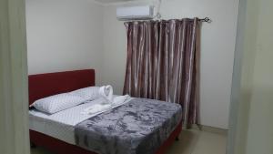 a bedroom with a bed with a red headboard and curtains at Blisful rental in Nadi