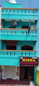 a blue building with a sign in front of it at Misha Residency in Virāmpattinam