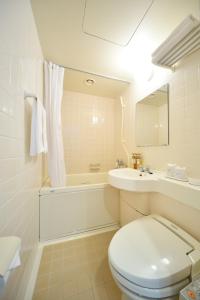 a white bathroom with a toilet and a sink at Uwajima Oriental Hotel in Uwajima