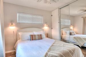 a bedroom with a white bed and a mirror at Beachside Bliss Spacious 3BR Retreat, Steps to Ocean in Oceanside