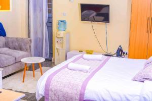 a bedroom with a bed and a couch and a tv at Sanquila Homes in Ruiru